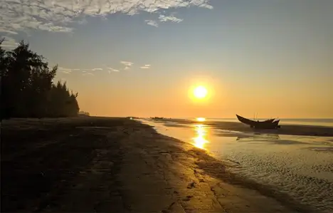 এটি সৈকতে একটি শান্ত ভোরের দৃশ্য। সোনালি সূর্য আকাশে নীচুতে রয়েছে, যার উষ্ণ আলো শান্ত জল এবং ভেজা বালির উপর প্রতিফলিত হচ্ছে। ডানদিকে, একটি ছোট মাছ ধরার নৌকা বালির উপর বিশ্রাম নিচ্ছে, যেন জোয়ারের জন্য অপেক্ষা করছে। সৈকতের বাম দিকে লম্বা গাছগুলি একটি শান্তিপূর্ণ এবং মনোরম পরিবেশ তৈরি করেছে।